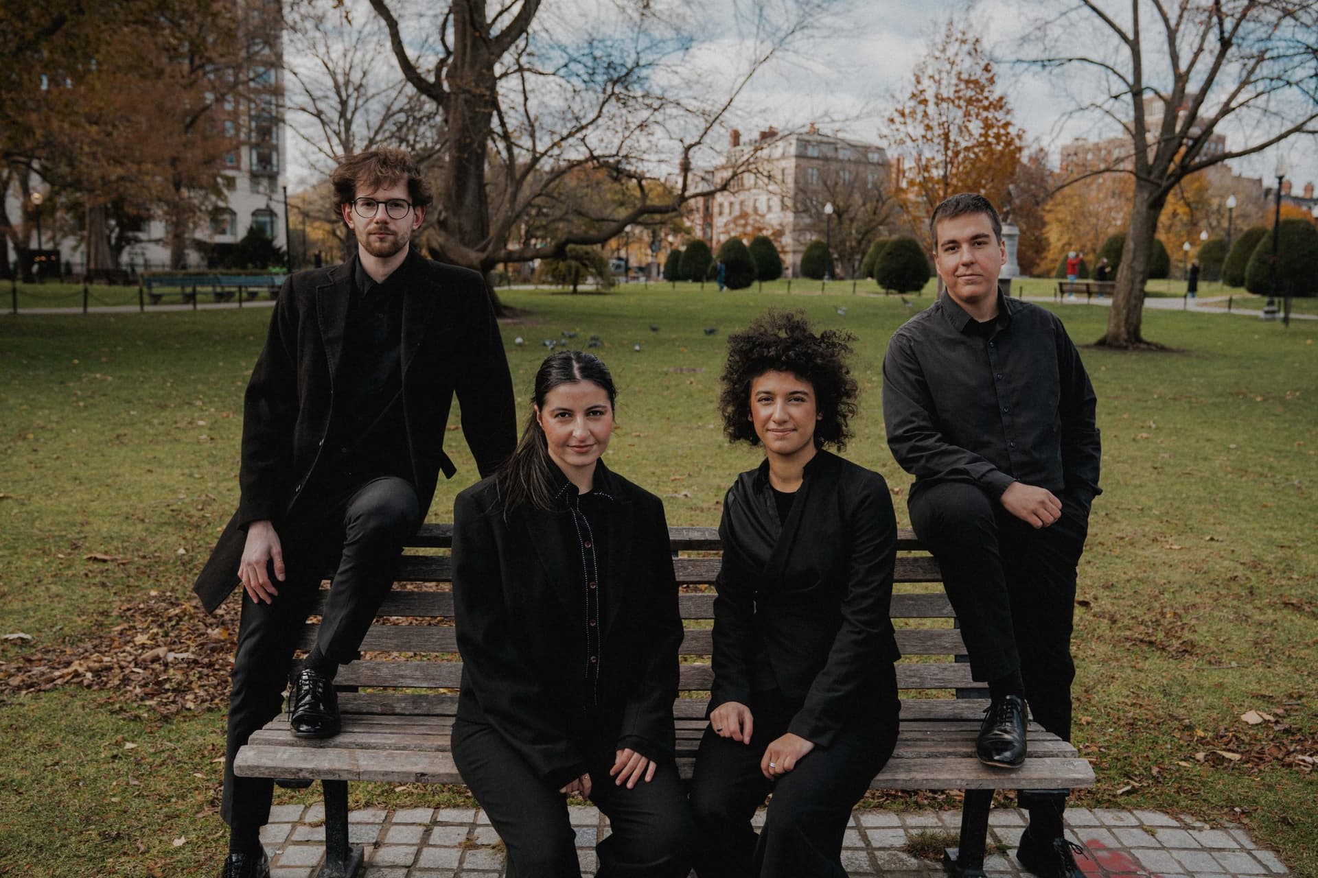 The four members of the quartet seated on a bench in a Boston park