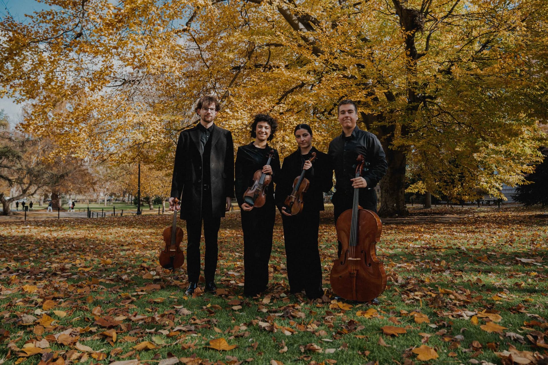 The quartet with their instruments in a park in autumn