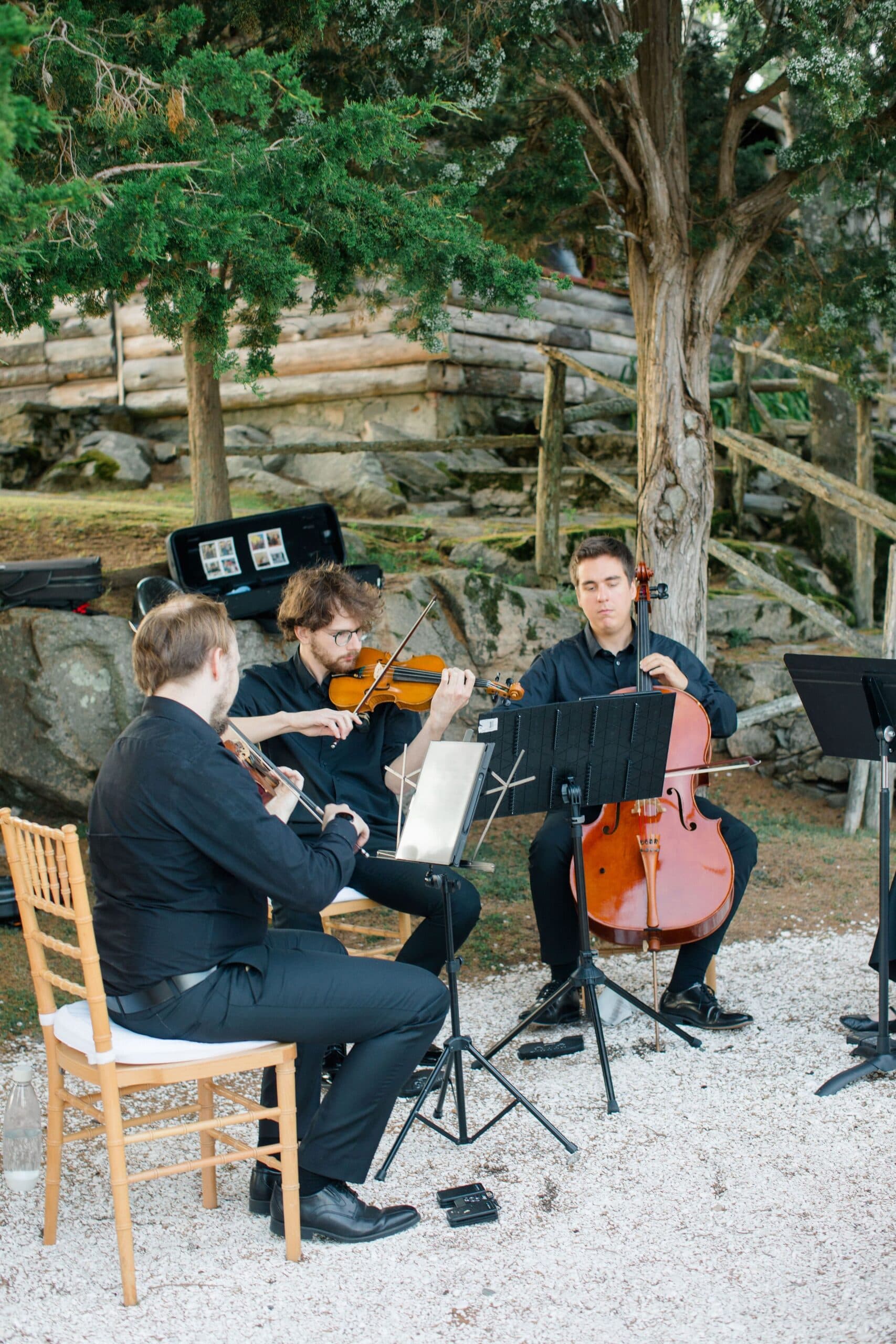 Trio performing beside a stone wall